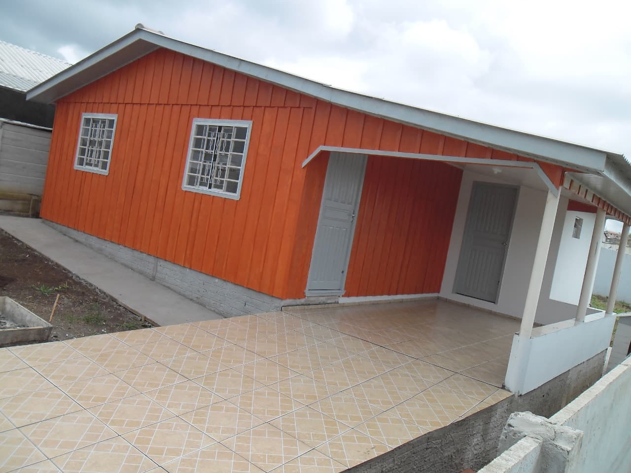 Casa laranja com ampla área coberta e piso