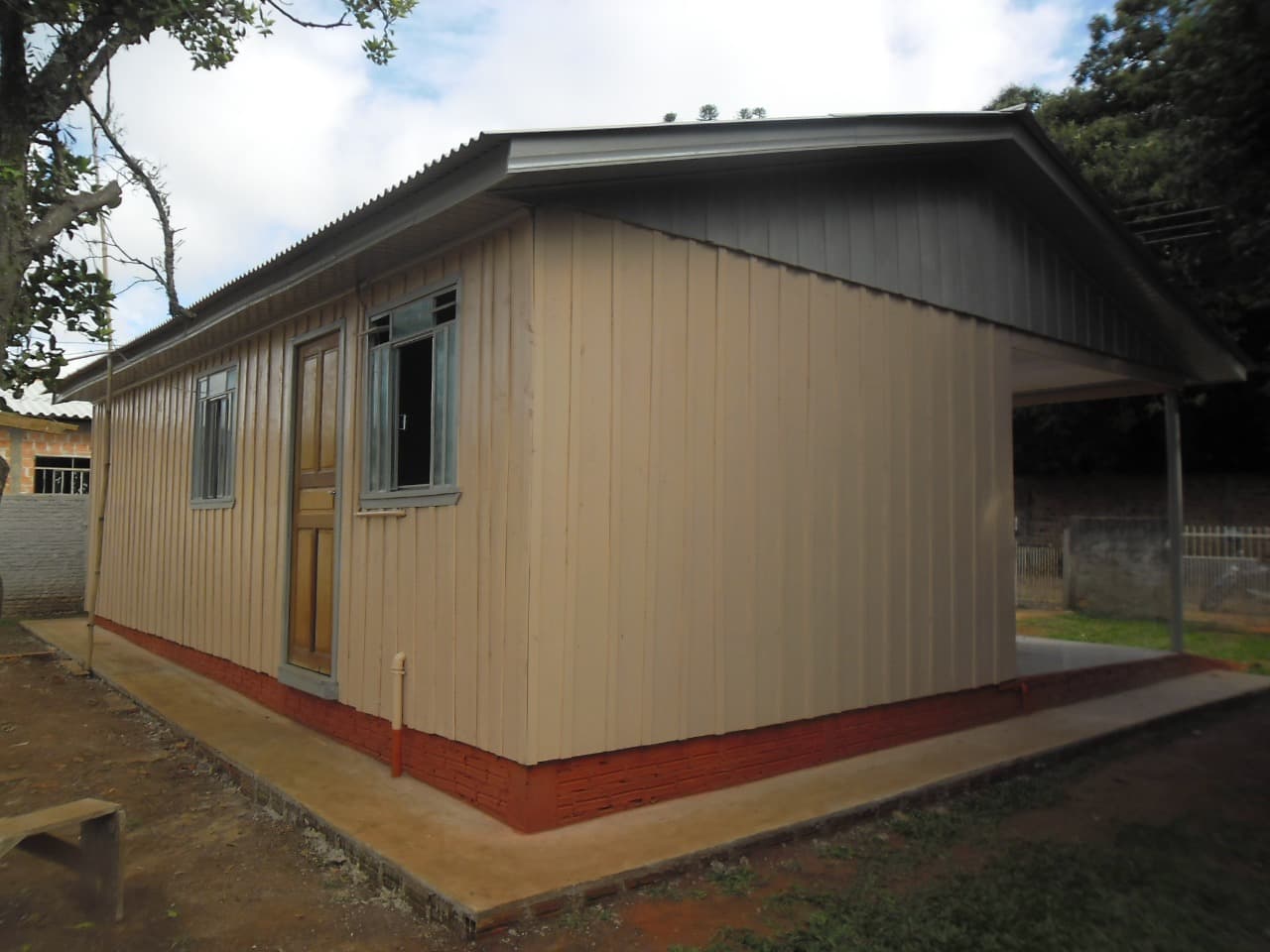 Casa com pintura bege e varanda lateral